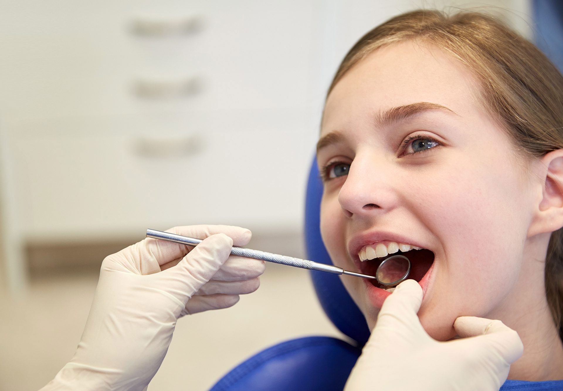 child getting dental check up, dentist looking at back teeth with hand held mirror.